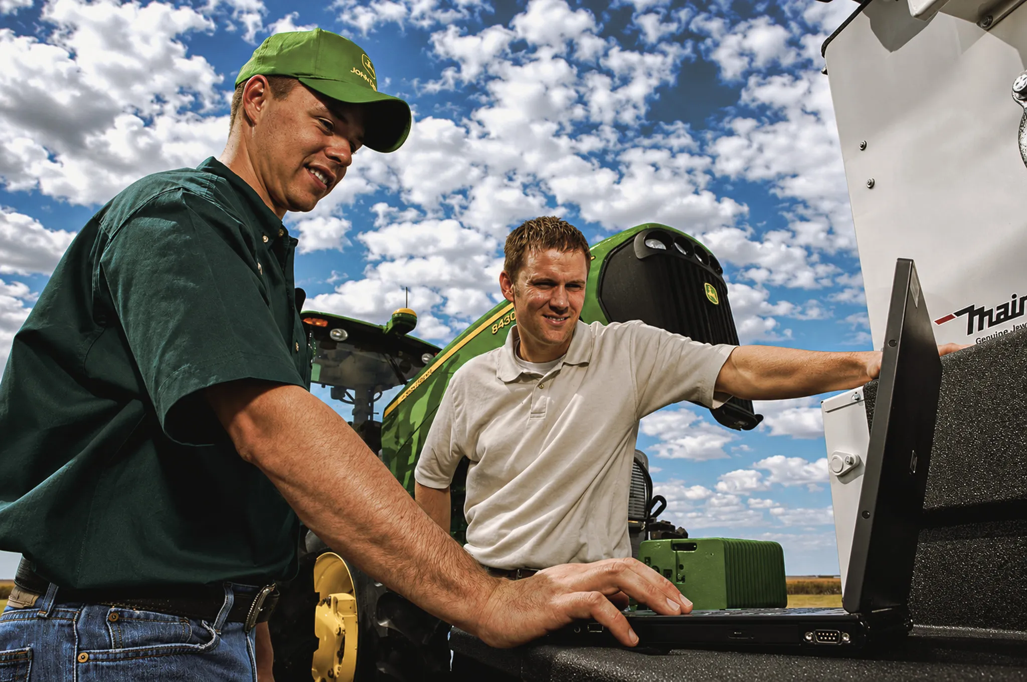 Dos concesionarios conversando junto a un tractor John Deere